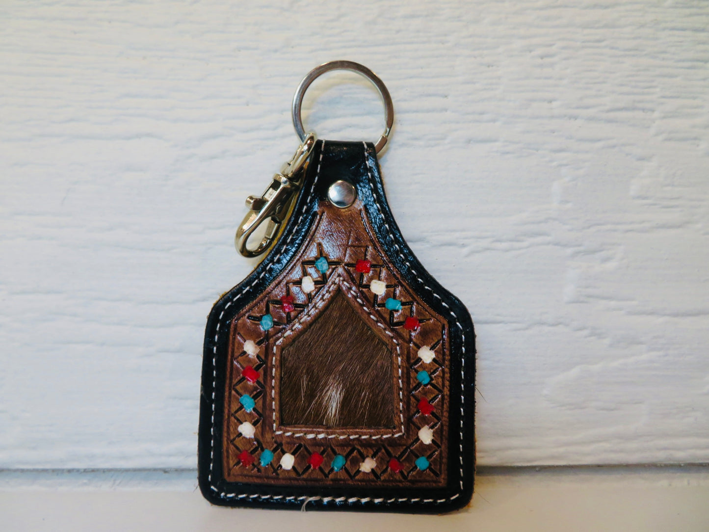 Tooled leather ear tag with cowhide