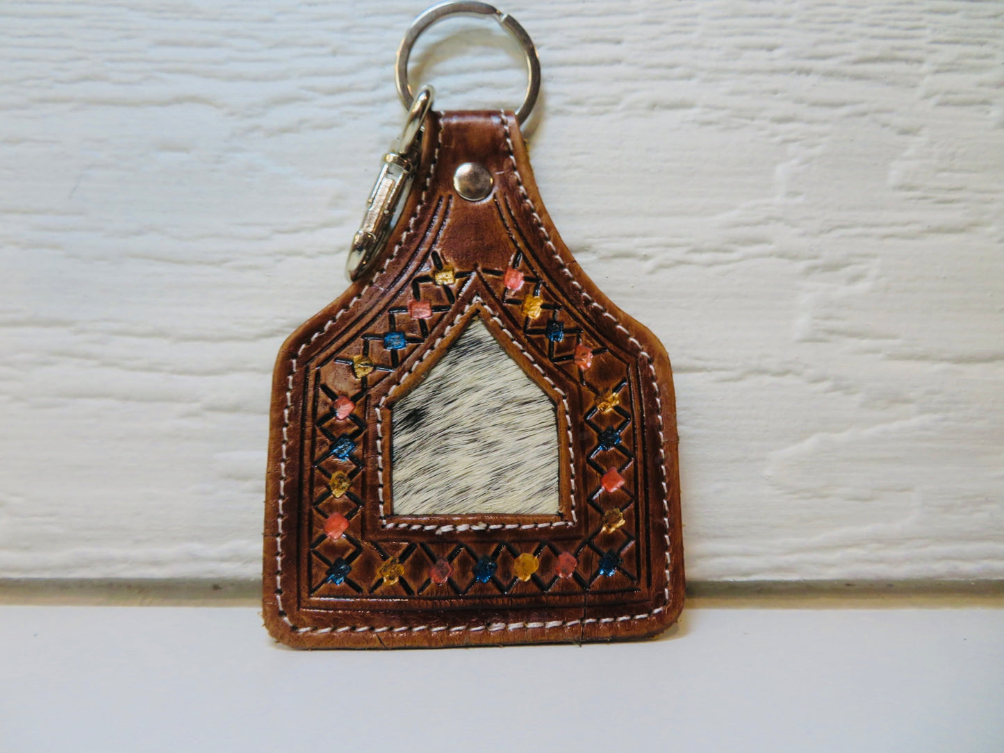 Tooled leather ear tag with cowhide